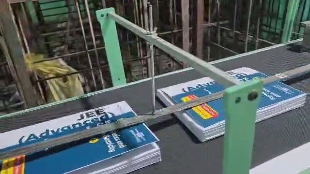 Books carried along a conveyor with side guides
